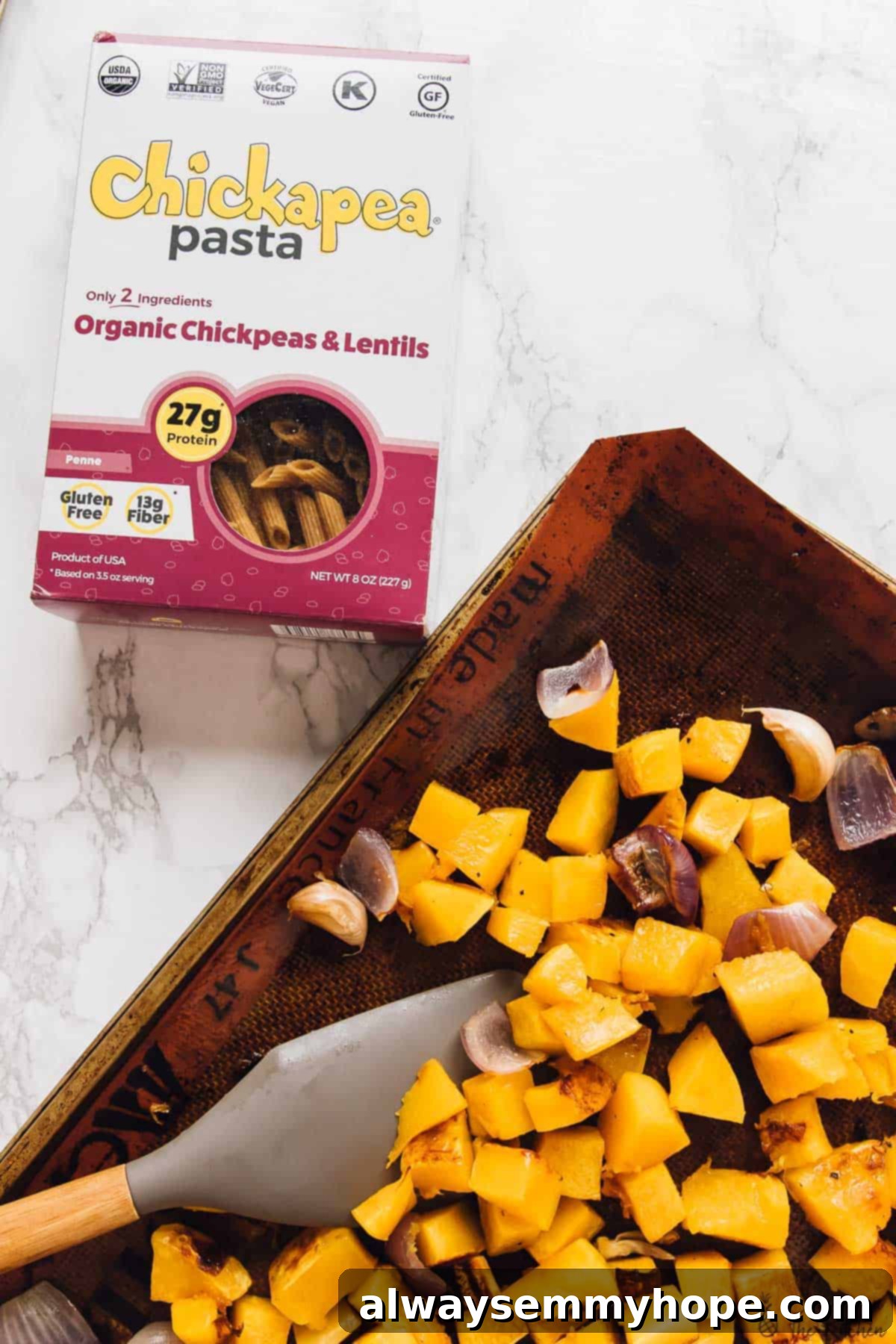 Overhead view of perfectly diced butternut squash pieces spread evenly on a baking tray, ready for roasting.