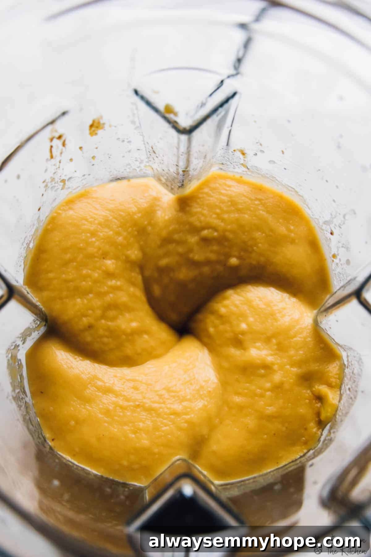 Smooth, creamy butternut squash soup swirling in a blender, ready for blending.