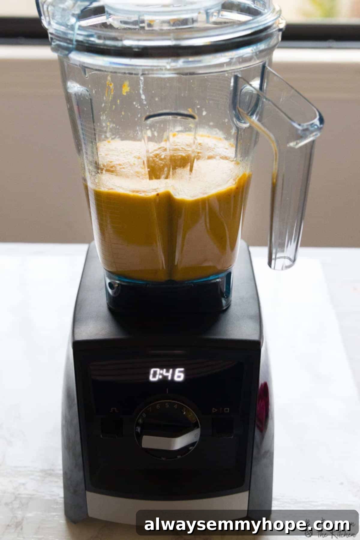 A side shot of creamy butternut squash mixture being blended to perfection in a Vitamix blender, highlighting its smooth texture.