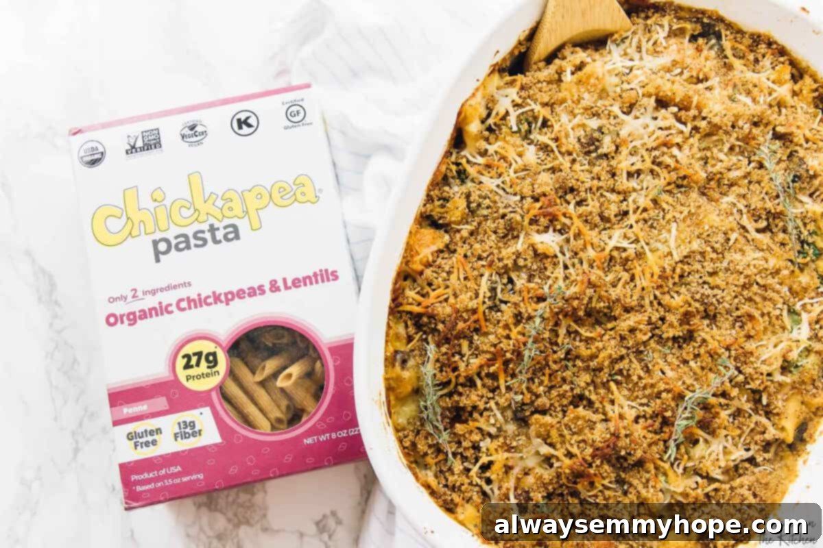 Overhead view of a golden-brown butternut squash pasta bake in a white baking dish, accompanied by a box of Chickapea pasta on the side, ready to be served.