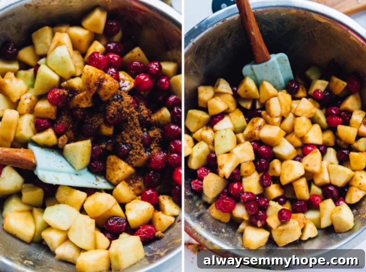 A silver bowl filled with diced apples and fresh cranberries, gently being mixed to combine before becoming a delicious crisp filling.