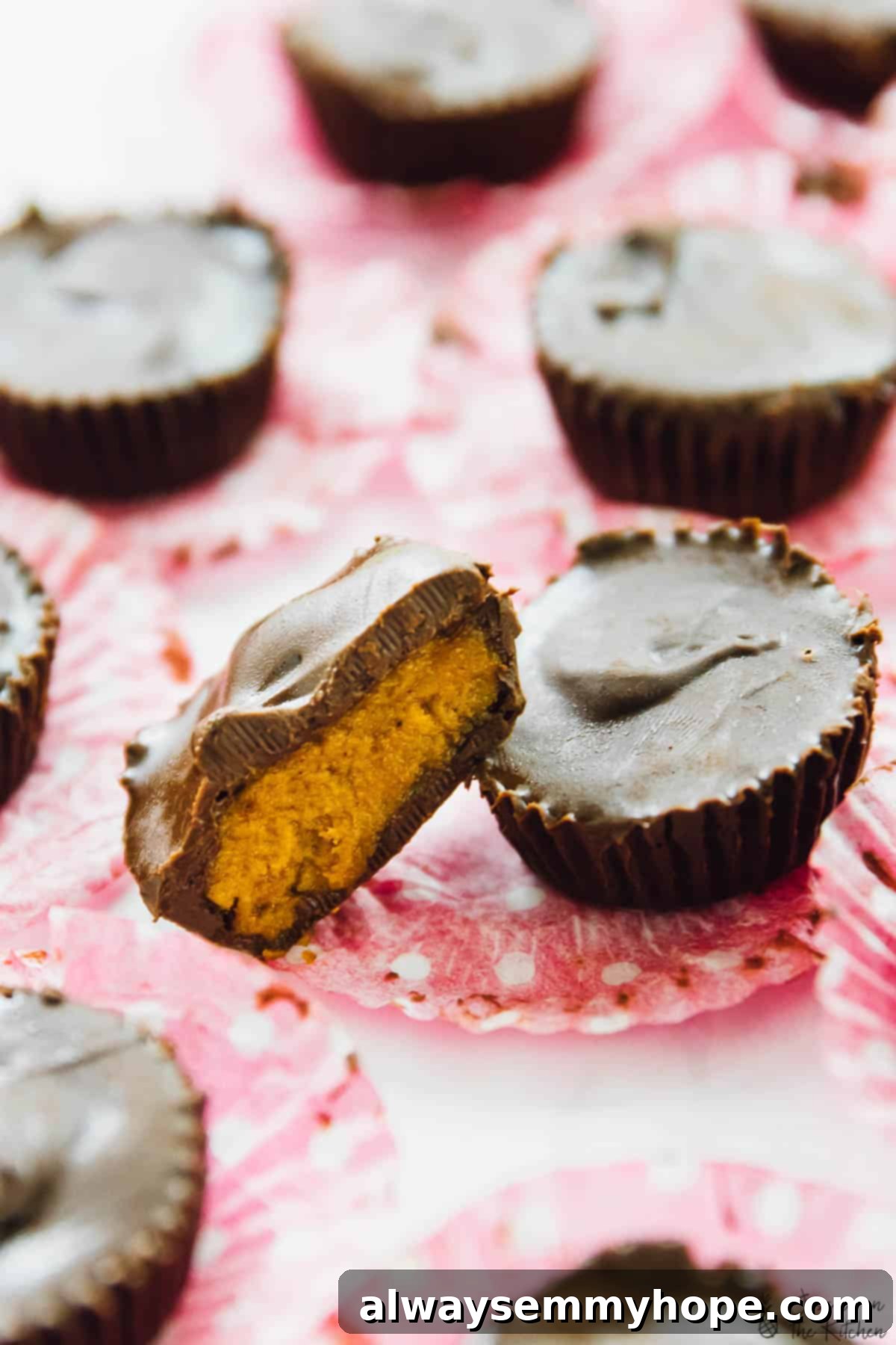 Chocolate cups cut in half on paper muffin liners, revealing the pumpkin filling.