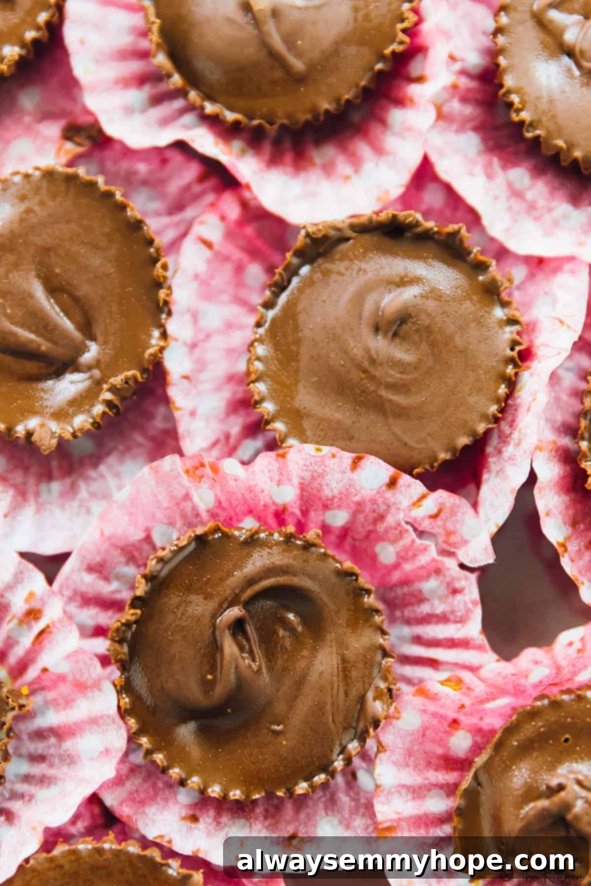 Top-down shot of pumpkin chocolate cups nestled in festive pink liners.