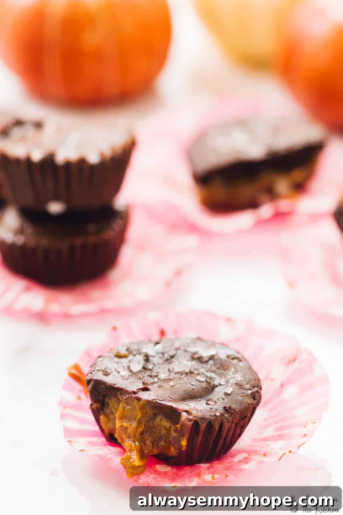 A perfectly made salted caramel chocolate cup with a bite taken out, revealing the glistening, soft caramel center and dark chocolate.