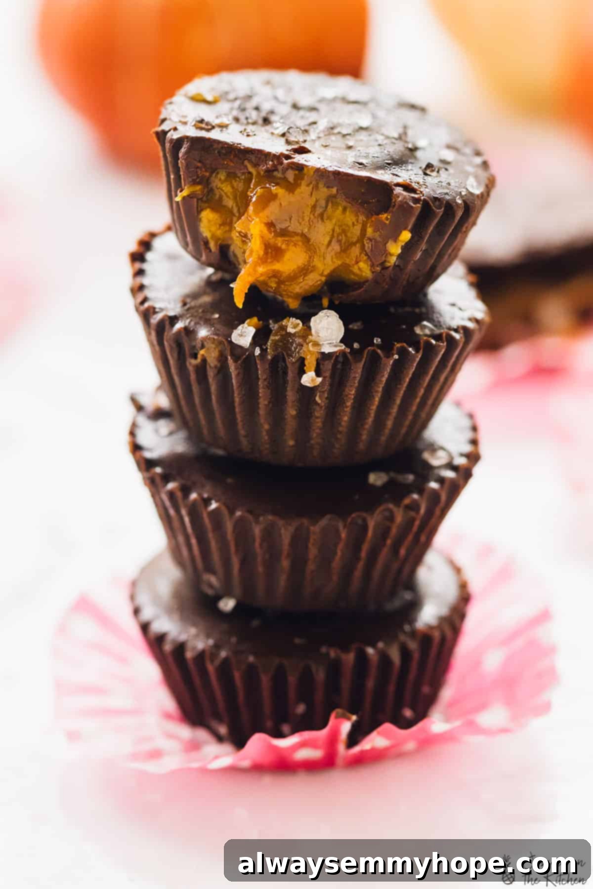 A beautifully arranged stack of four salted caramel chocolate cups, artfully presented on a delicate pink liner, ready to be served.