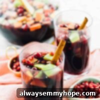Two glasses of festive red wine sangria, garnished with fresh fruit, elegantly displayed on an orange cloth, ready for a fall gathering.