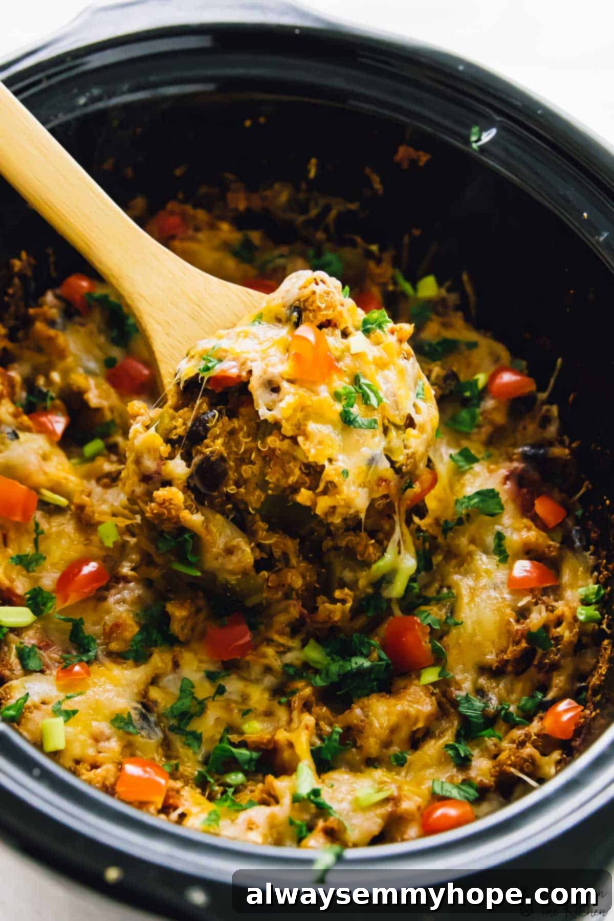 A vibrant slow cooker quinoa enchilada casserole being scooped out of a black pot, showcasing its rich textures and colors.