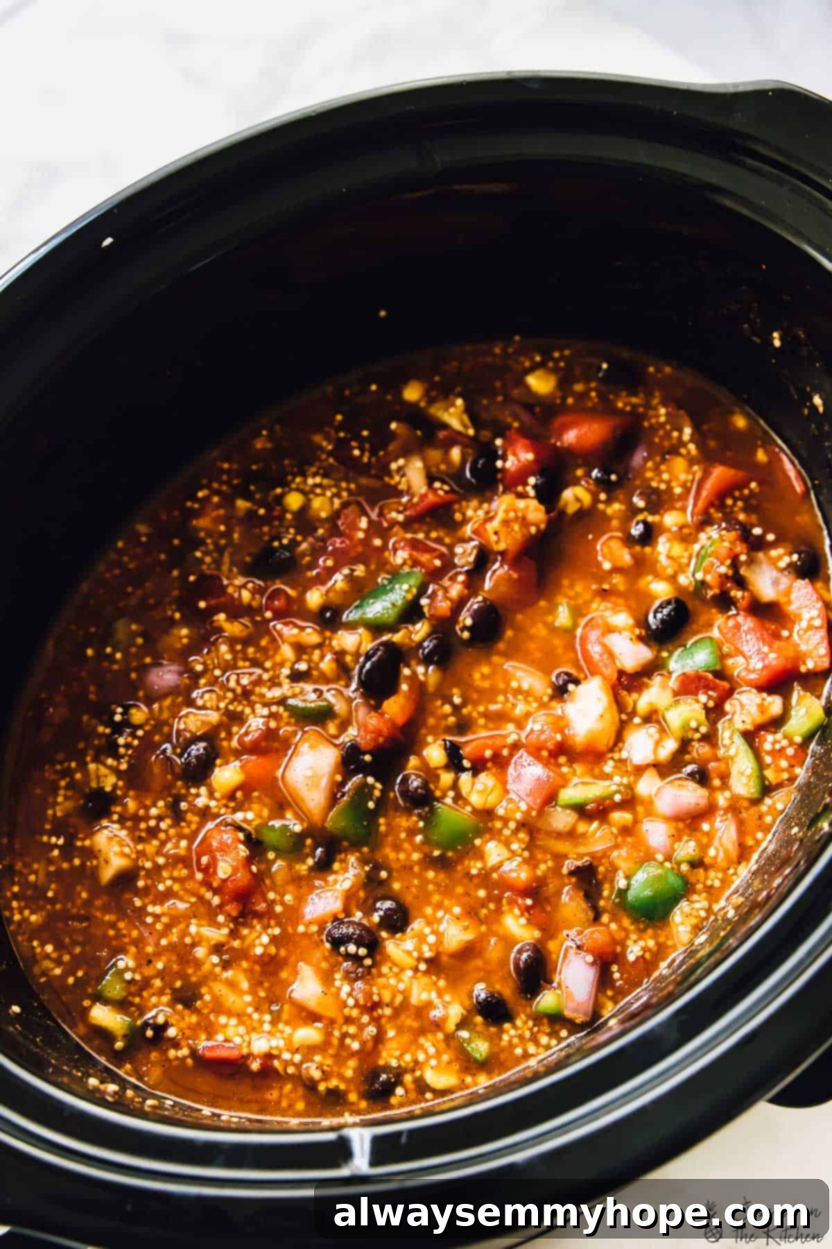 A rich, slow cooker quinoa enchilada casserole simmering in a black crockpot, ready to serve.