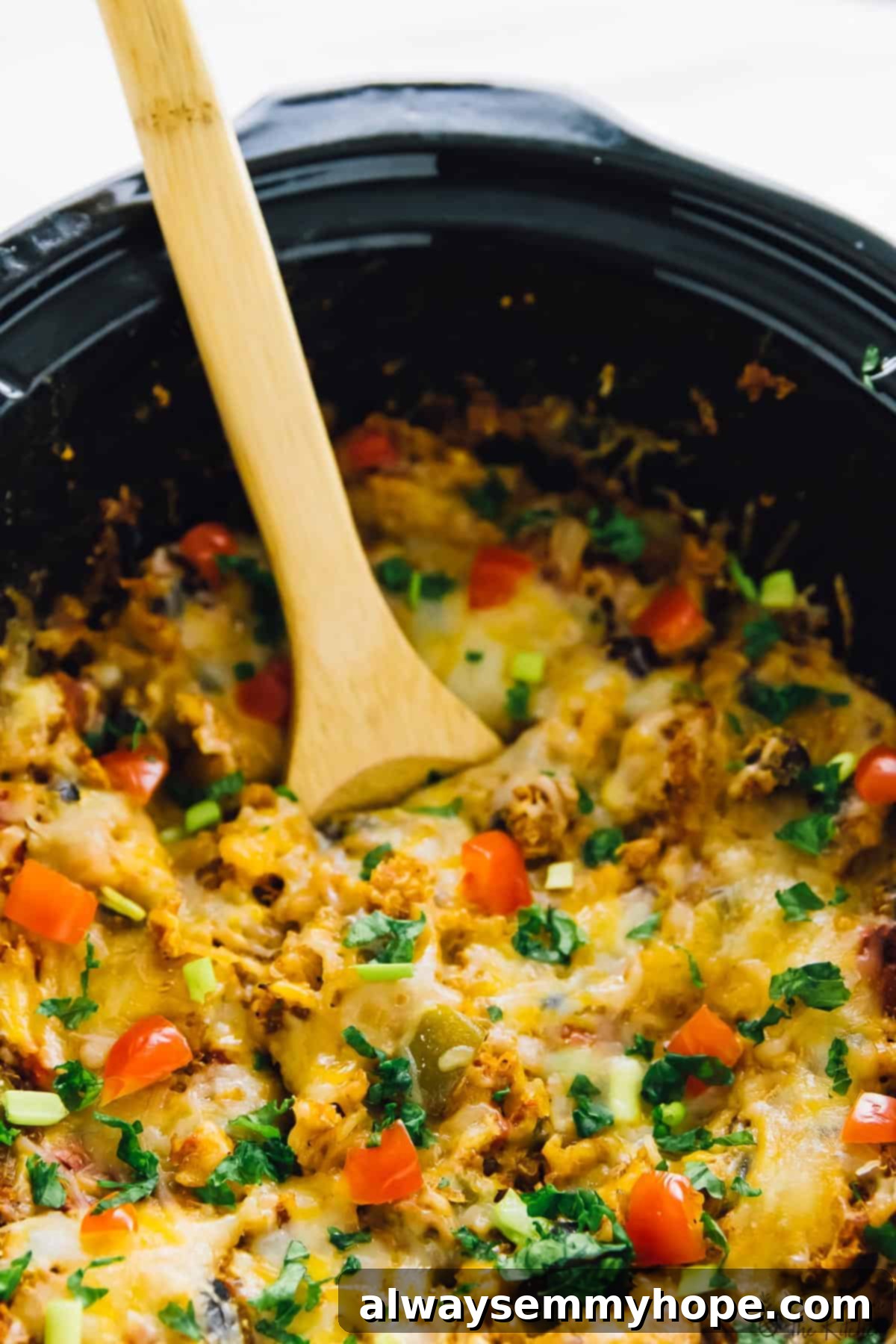 A wooden spoon gently stirring a delicious slow cooker quinoa enchilada casserole, showcasing the mix of ingredients.