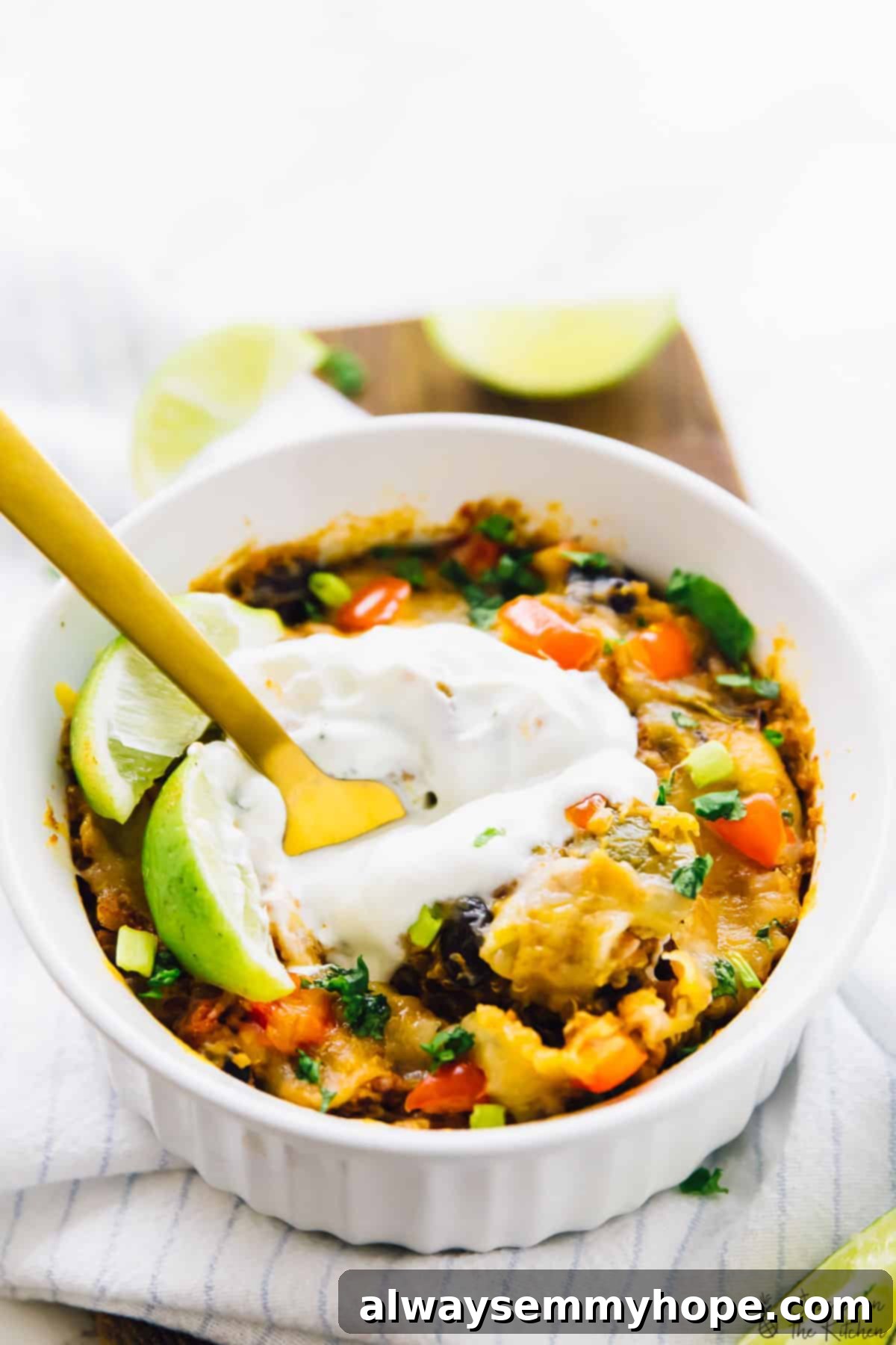 A small white ramekin filled with slow cooker quinoa enchilada casserole, adorned with a gold fork, ready to be enjoyed.