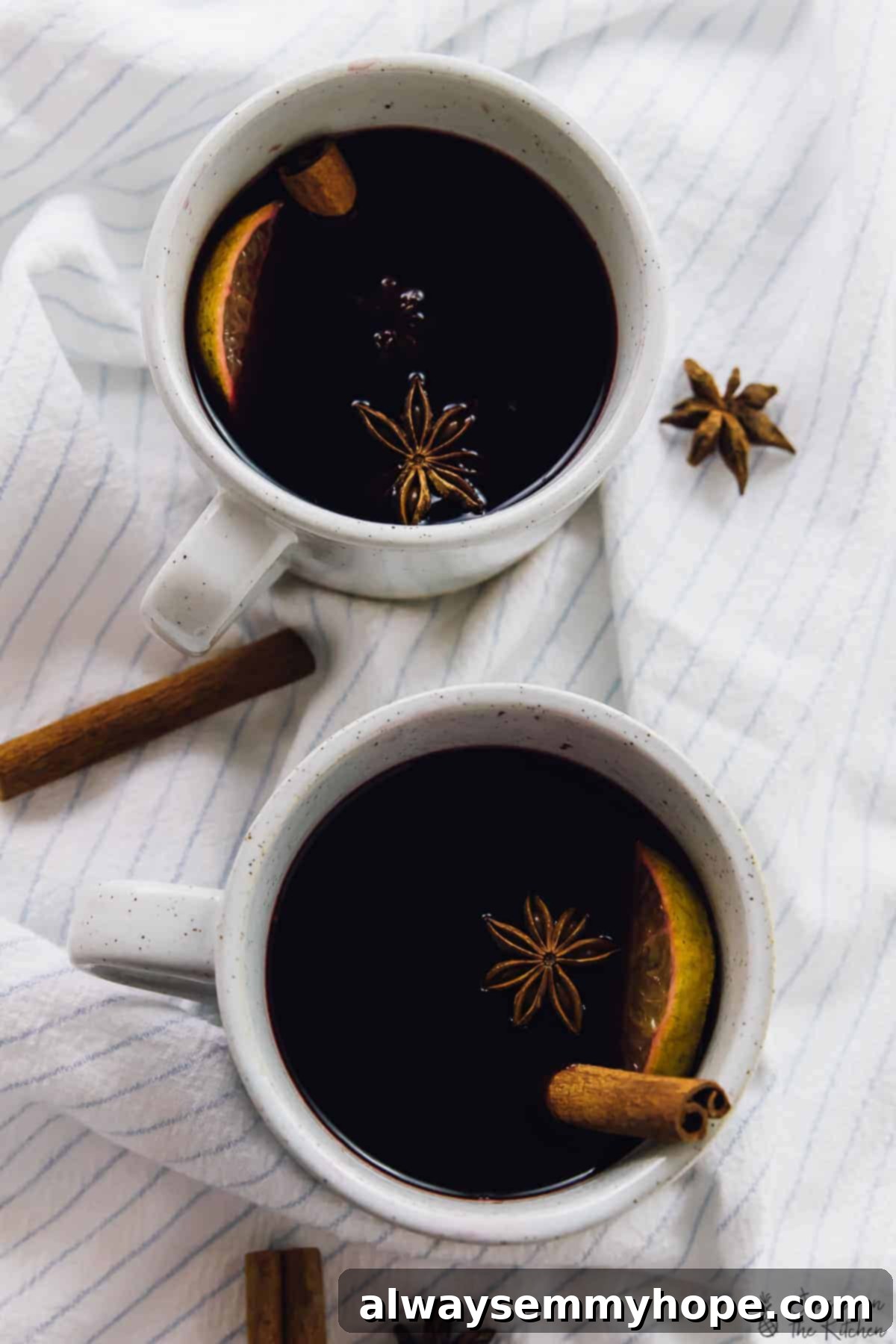 An inviting overhead shot of two mugs of mulled wine, beautifully garnished with fragrant cinnamon sticks and delicate star anise, perfectly capturing a cozy, festive ambiance.
