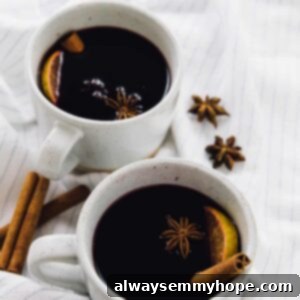 Two mugs of mulled wine on a striped cloth, ready to be enjoyed.