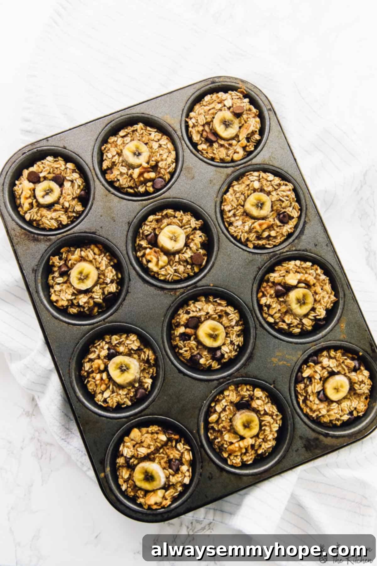 Overhead view of baked banana bread oatmeal cups in a muffin mold, showcasing their golden-brown tops.