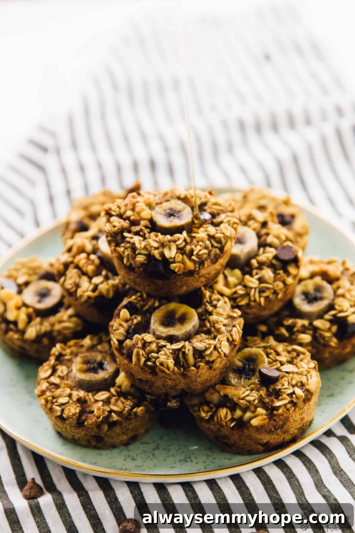 A batch of baked banana bread oatmeal cups on a green plate, being drizzled with a golden syrup.