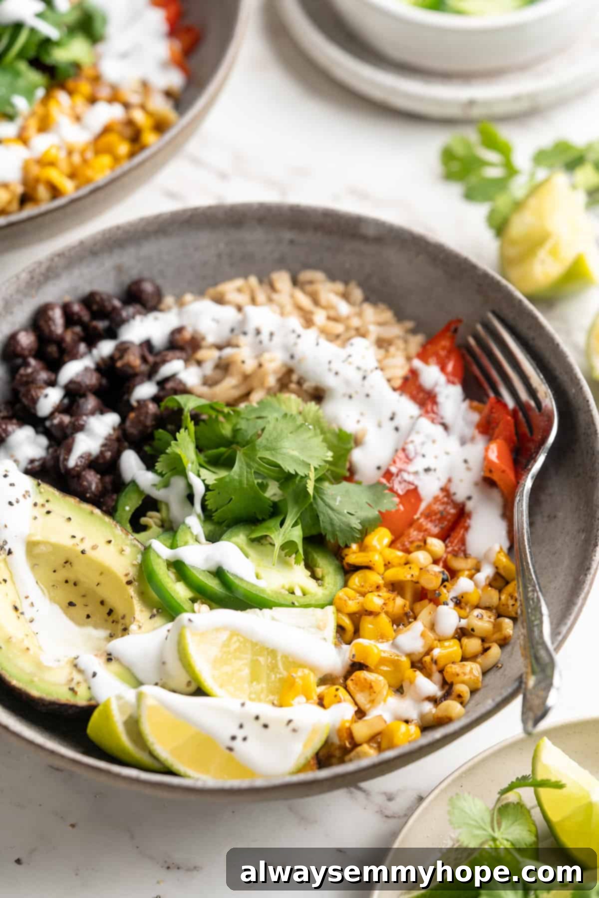A close-up shot of a single vegan burrito bowl with charred corn, fresh avocado, jalapeños, and a generous drizzle of lime crema.