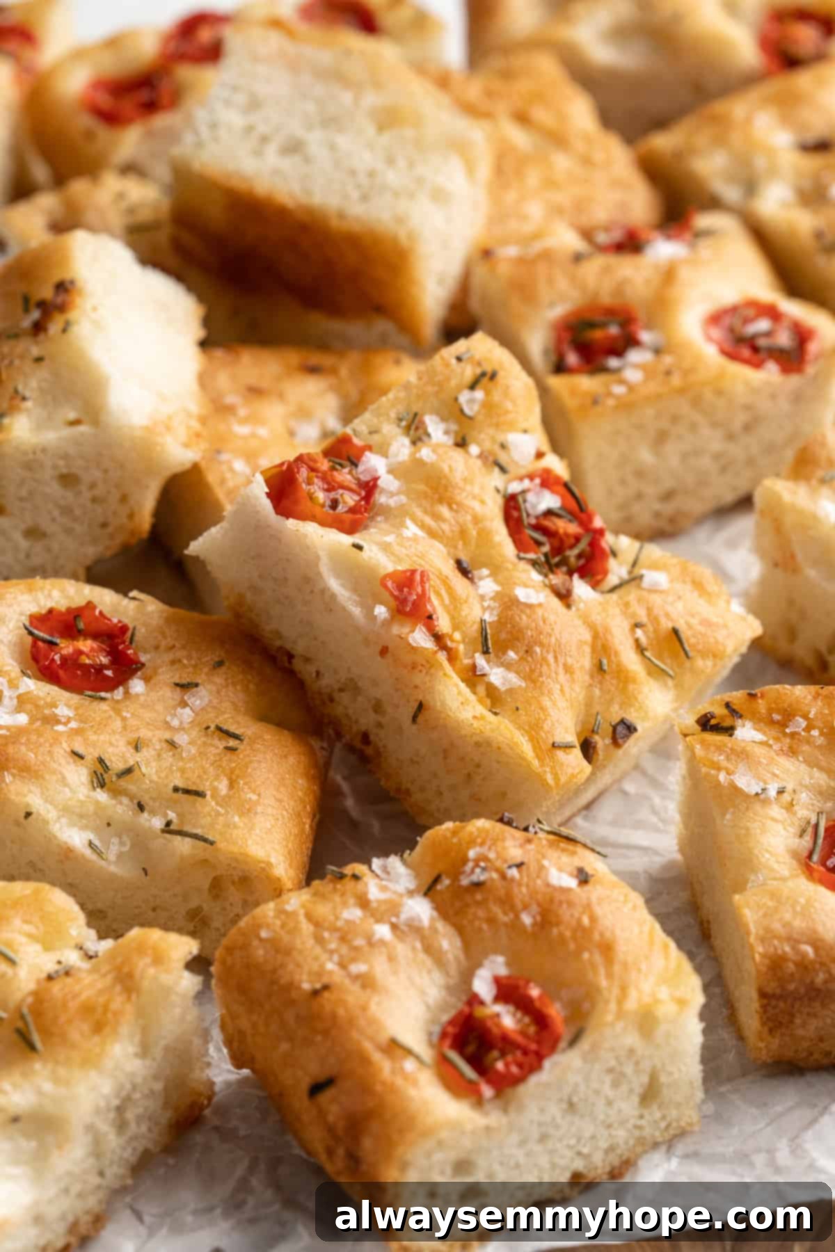 A pile of freshly baked gluten-free focaccia slices, golden and inviting, resting on parchment paper.