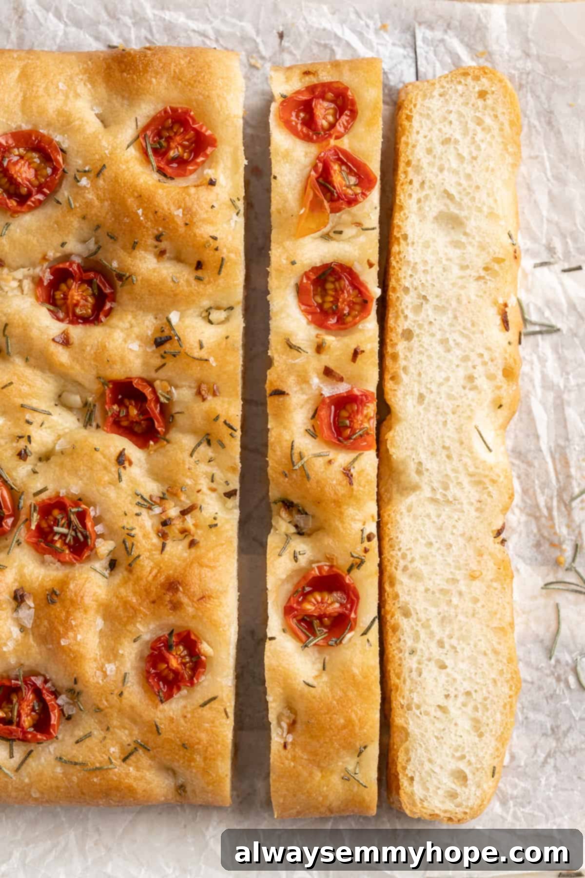 Slices of fluffy gluten-free focaccia bread, beautifully topped with juicy cherry tomatoes and fresh rosemary sprigs.