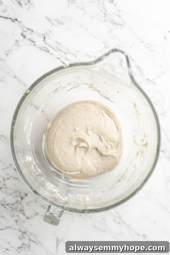 Freshly mixed gluten-free focaccia dough in a glass bowl, covered and ready for its first rise.
