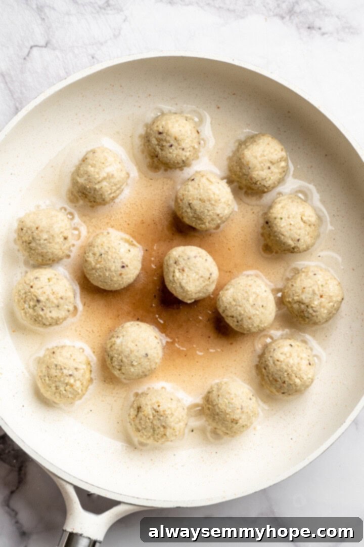 Buffalo cauliflower meatballs cooking in skillet.