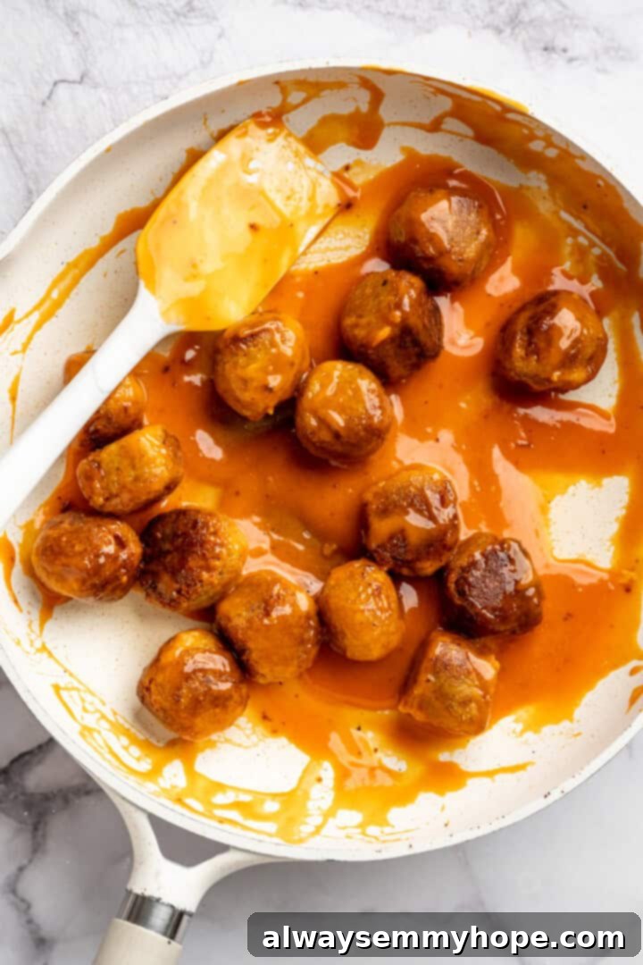 Cauliflower meatballs in skillet with Buffalo sauce.