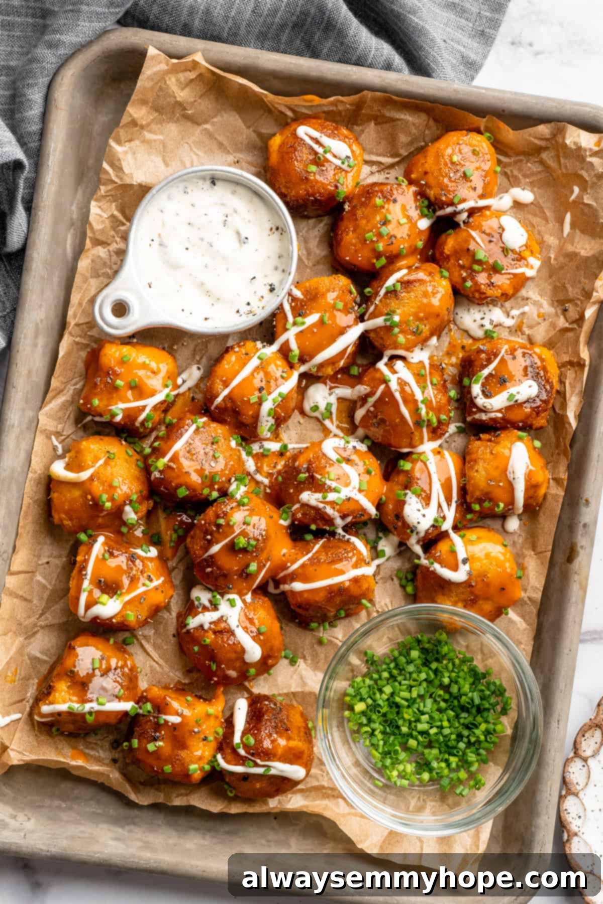 Sheet pan with Buffalo cauliflower meatballs, ranch dressing, and chives in bowl.