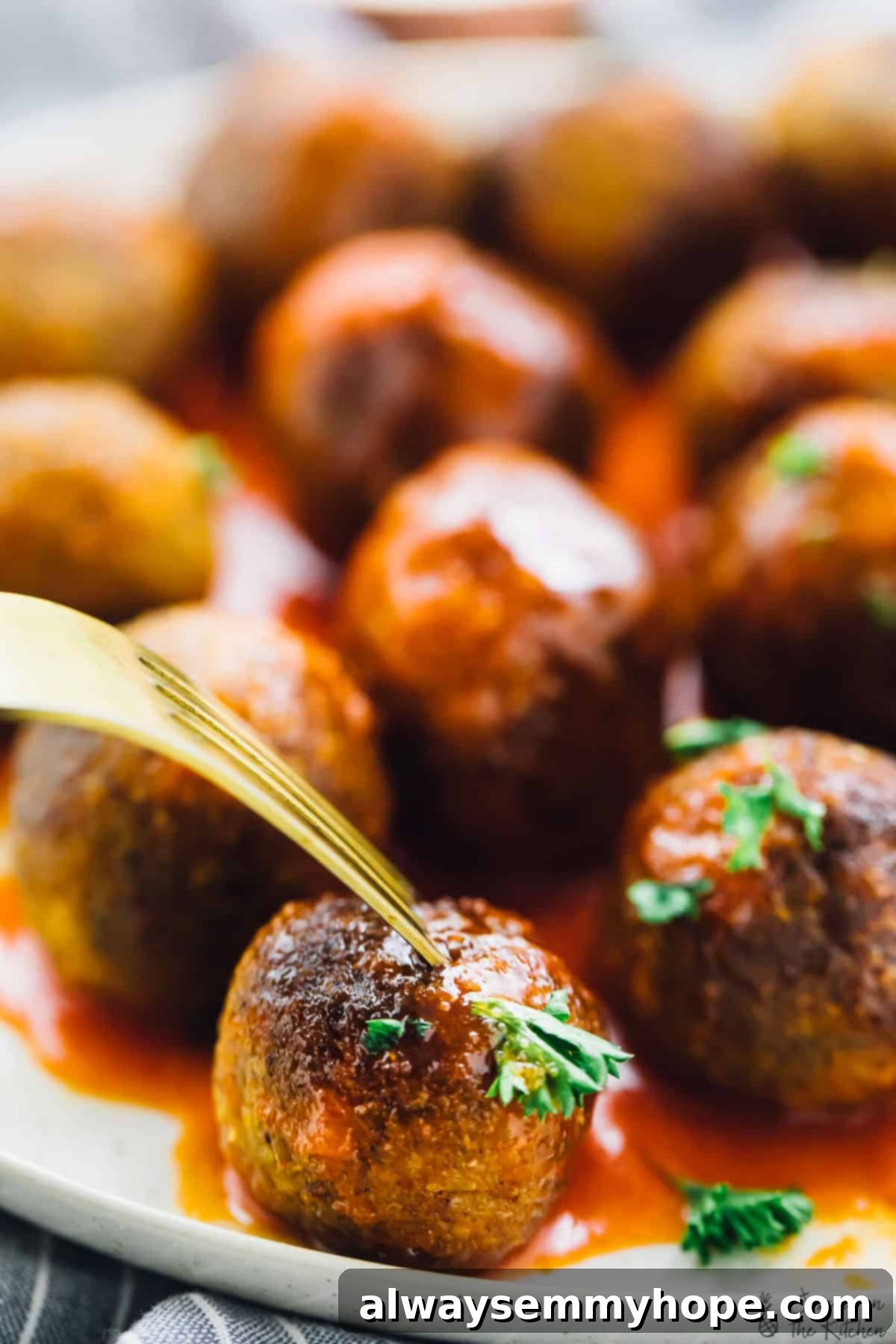 Buffalo-Style Vegan Quinoa Cauliflower Meatballs 4 A gold fork digging into a vegan meatball.