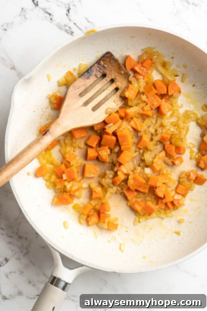 Get the party started with loaded nacho fries! They're topped with all your favourite nacho toppings to create an irresistible appetizer. Overhead view of chopped carrots, onions, and garlic sautéing in a pan, forming the aromatic base for the vegan cheese sauce.