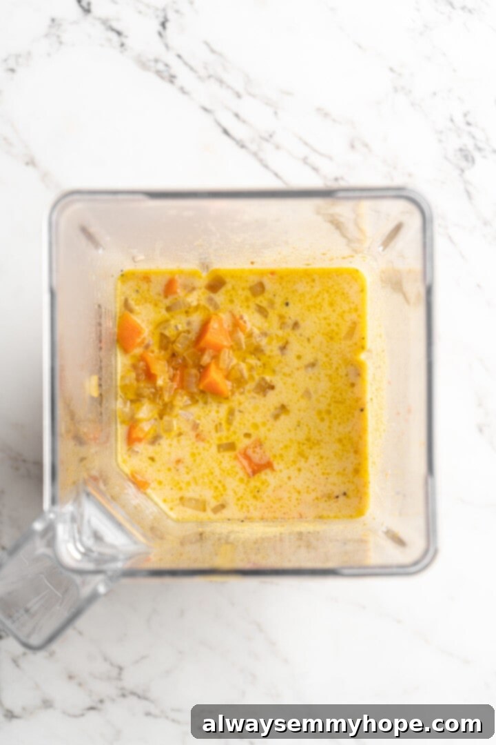 Get the party started with loaded nacho fries! They're topped with all your favourite nacho toppings to create an irresistible appetizer. Overhead view of all vegan queso ingredients, including sautéed vegetables, cashews, nutritional yeast, and spices, gathered in a blender jar.