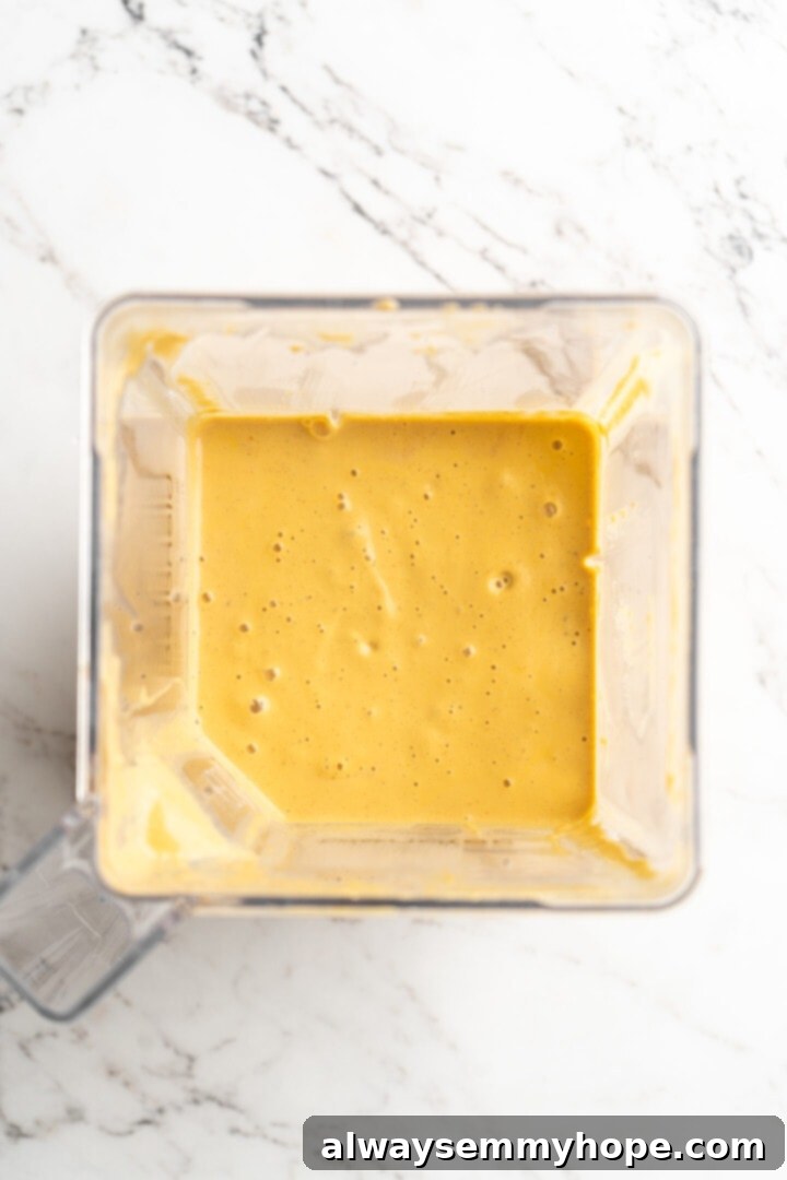 Get the party started with loaded nacho fries! They're topped with all your favourite nacho toppings to create an irresistible appetizer. Overhead view of the creamy, smooth vegan queso blending in a high-speed blender, demonstrating its rich, vibrant texture.