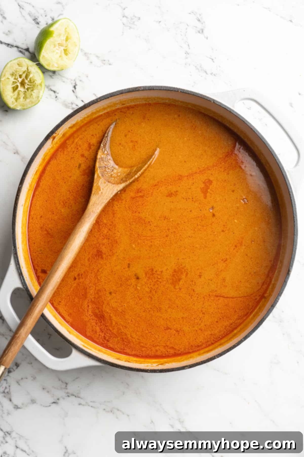 This Thai Coconut Curry Soup is creamy, flavourful, and fragrant, with plenty of veggies and noodles to keep you satisfied. Quick and easy! Overhead view of a creamy red coconut curry broth for Thai coconut curry soup, garnished with fresh basil leaves.