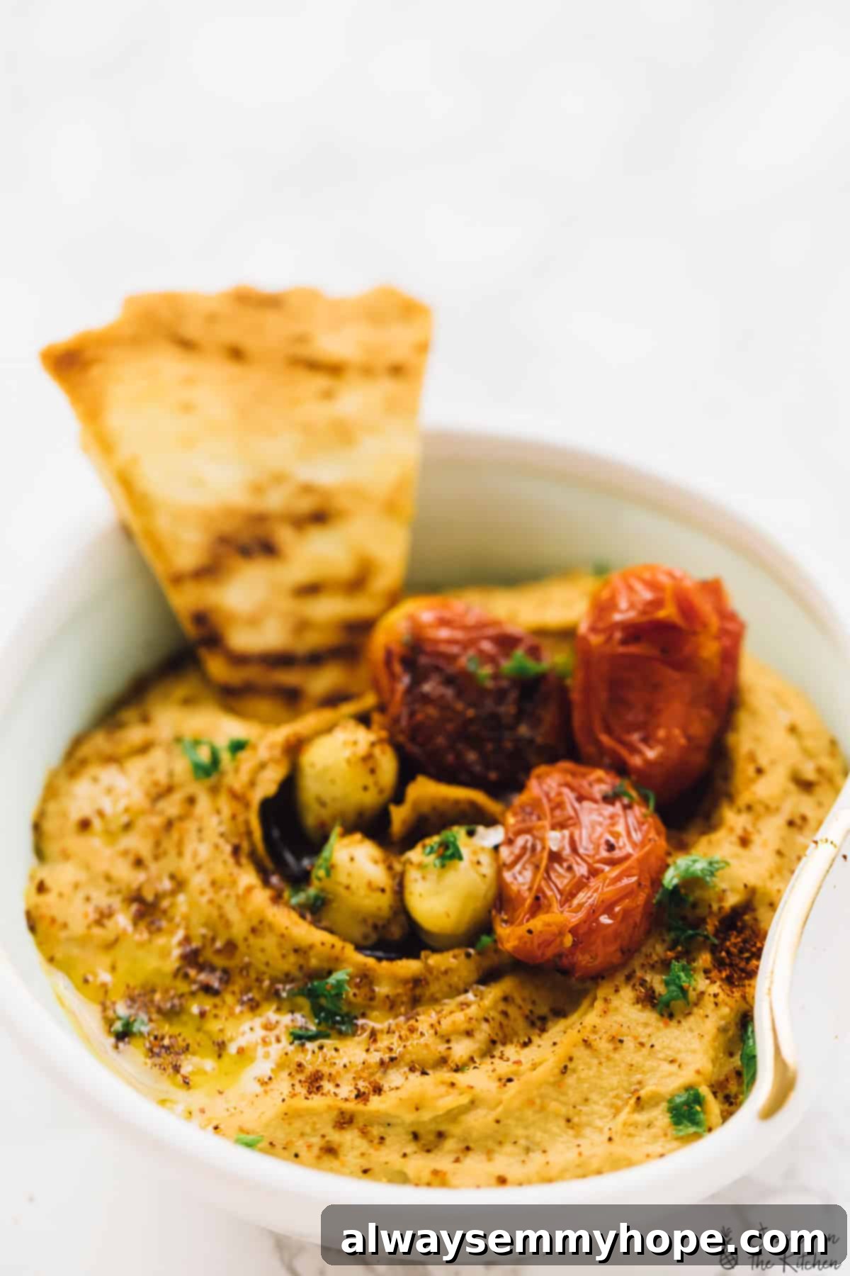 This roasted red pepper hummus recipe is sweet, savoury, smoky, and spicy. It's easy to make and ready to impress! Bowl of roasted red pepper hummus with pita chips