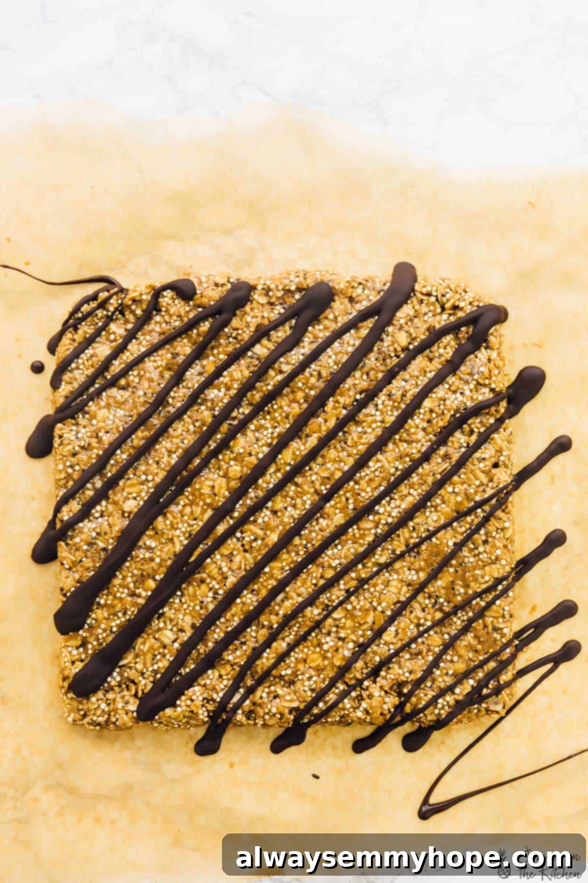 No-Bake Salted Honey Dark Chocolate Quinoa Coconut Delights 5 A large slab of no-bake granola bar mixture, beautifully drizzled with rich, melted dark chocolate and sprinkled with sea salt, showcasing the delicious texture before cutting.