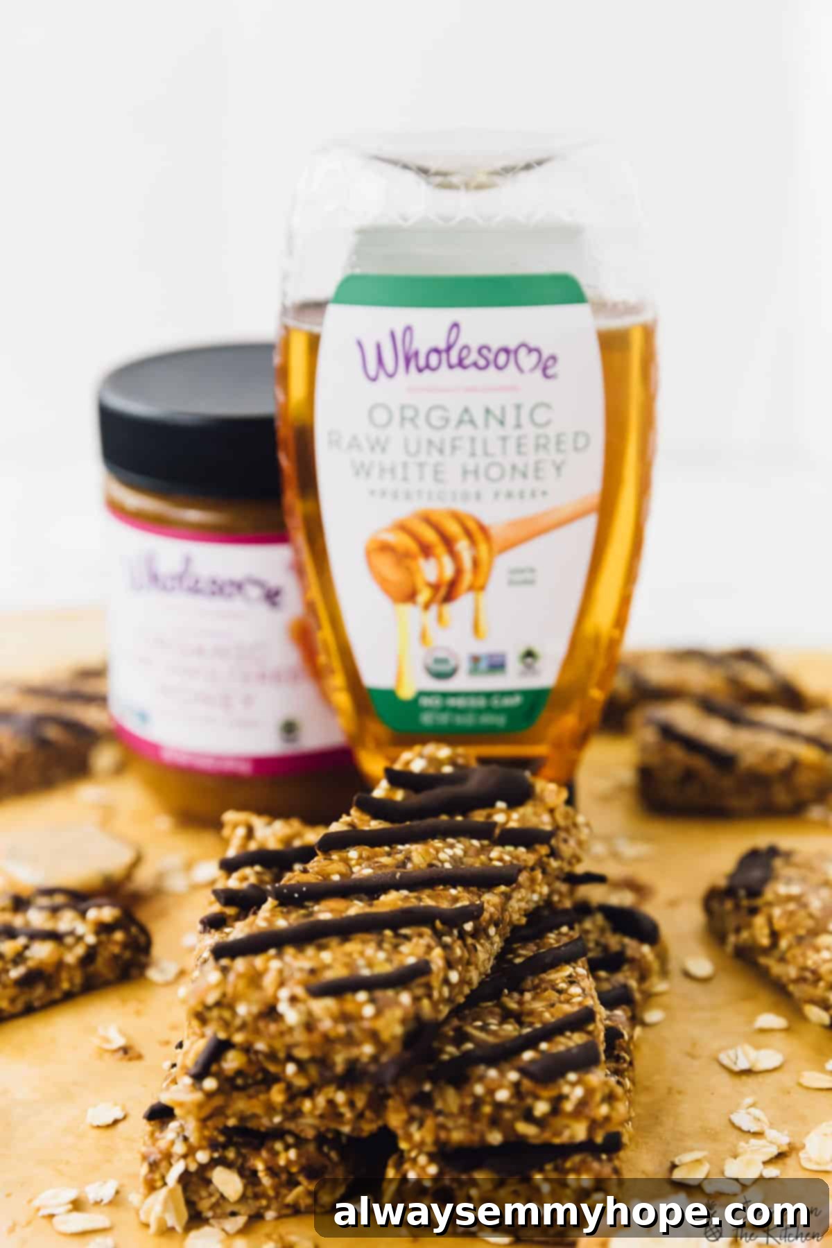 No-Bake Salted Honey Dark Chocolate Quinoa Coconut Delights 7 A rustic stack of five perfectly layered no-bake granola bars on a wooden board, with a blurred bottle of Wholesome Honey in the background, emphasizing their homemade appeal and natural ingredients.