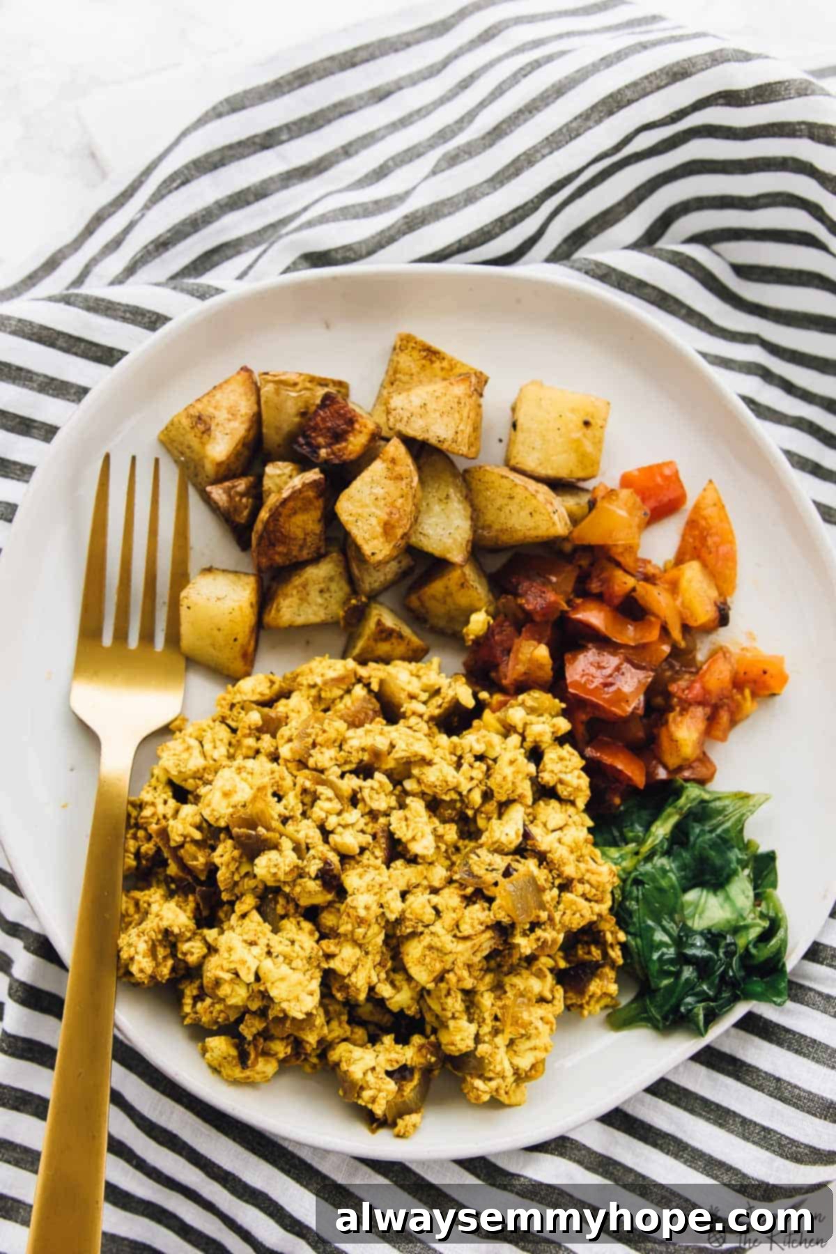 A hearty portion of Southwestern tofu scramble served on a plate with roasted potatoes and colorful bell peppers, showcasing a complete vegan meal.