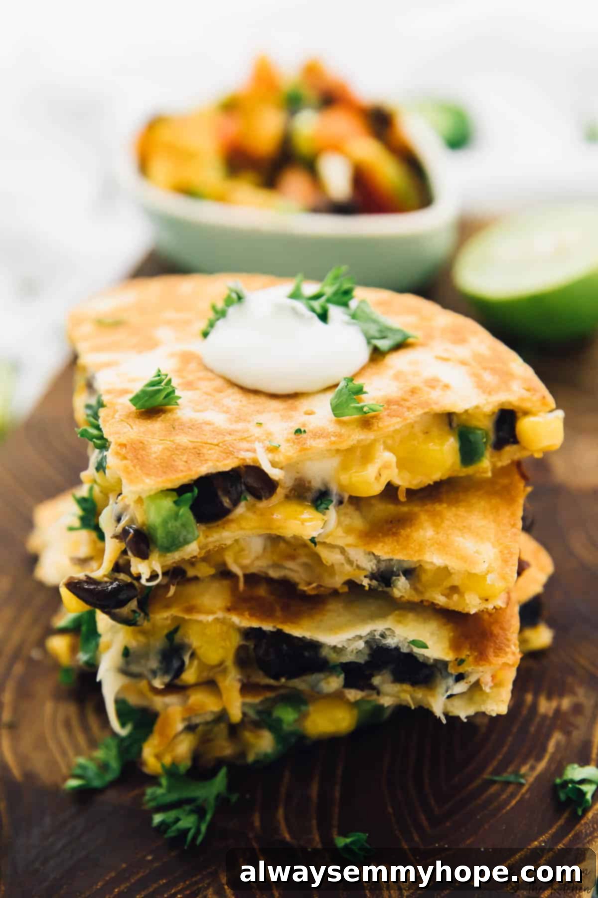 These easy black bean and corn quesadillas are done in just 15 minutes, making them perfect for a quick weeknight dinner! Stack of crispy black bean and corn quesadilla wedges on a rustic wooden board, garnished with fresh cilantro.