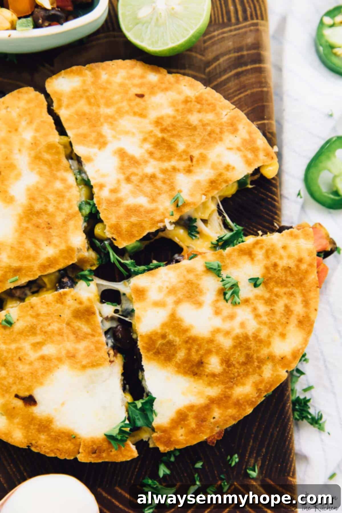 These easy black bean and corn quesadillas are done in just 15 minutes, making them perfect for a quick weeknight dinner! Overhead view of a single vegan black bean and corn quesadilla, sliced into wedges, on a white plate with a side of vegan sour cream and cilantro garnish.