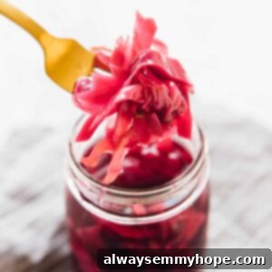 The Ultimate Quick Pickling Guide Cabbage & Every Vegetable 6 Purple quick pickled cabbage held up by a fork over a jar of more quick pickled cabbage in a glass jar.