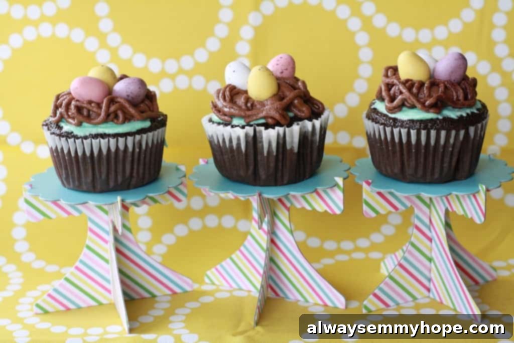Cute Bird's Nest Easter Cupcakes. Easy to make and fun to eat, with chocolate Easter eggs to set them off. Three individual bird's nest cupcakes presented on mini cake stands, showcasing their detailed decoration.
