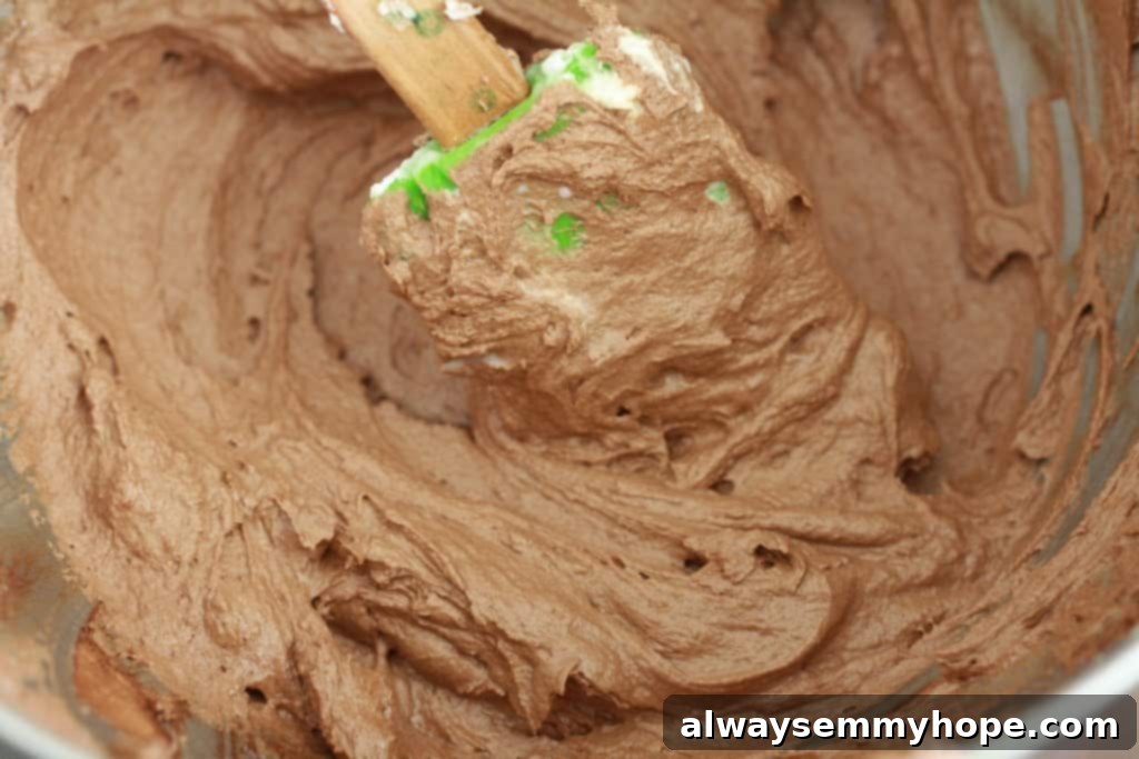 Cute Bird's Nest Easter Cupcakes. Easy to make and fun to eat, with chocolate Easter eggs to set them off. Spatula mixing luscious chocolate cupcake frosting in a bowl.