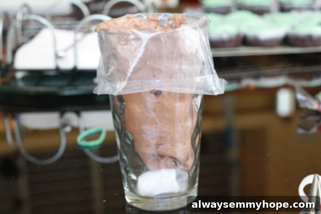 Cute Bird's Nest Easter Cupcakes. Easy to make and fun to eat, with chocolate Easter eggs to set them off. Piping bag held upright in a glass, being filled with rich chocolate frosting.
