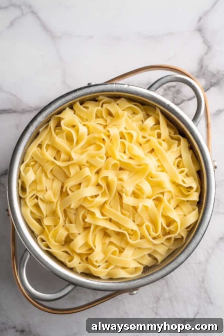 Overhead view of cooked fettuccine in a colander, ready to be drained.