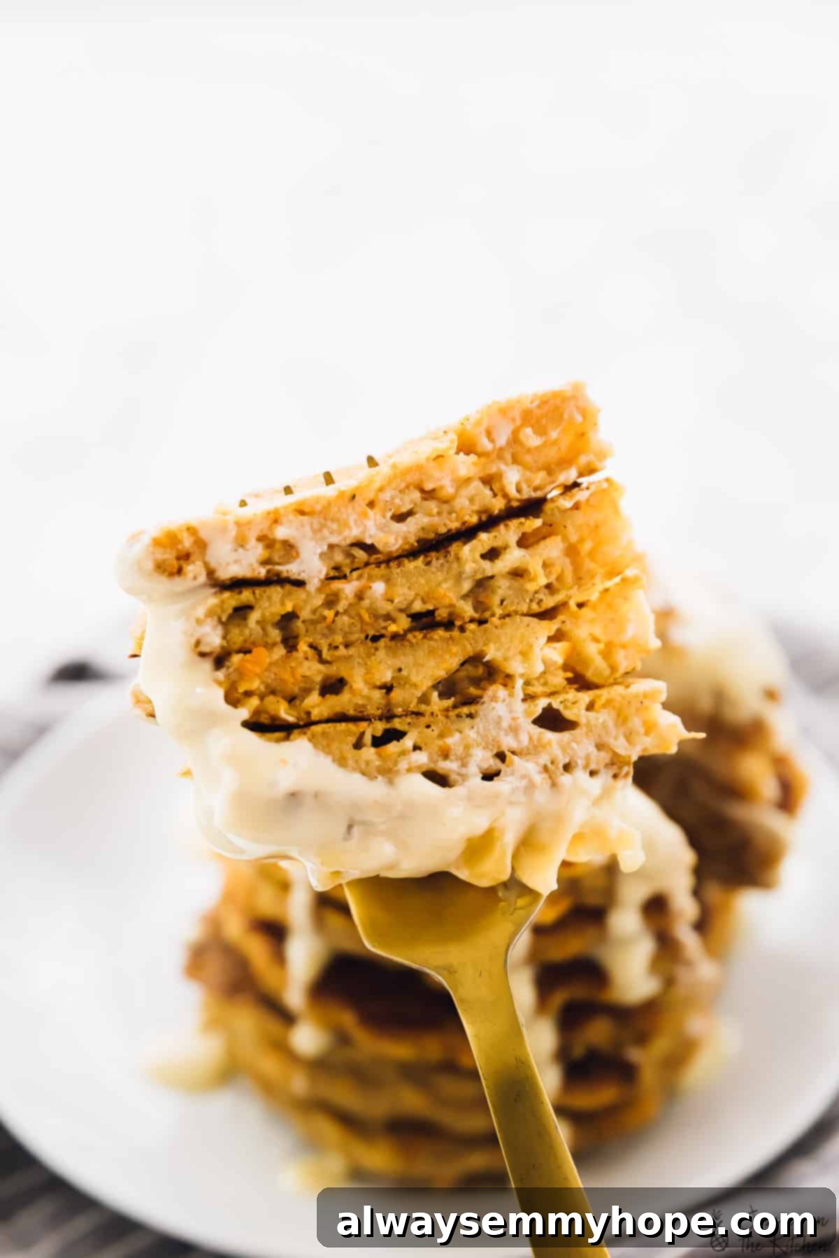 Vegan Carrot Cake Pancakes with Maple Cream Cheese 3 Close-up shot of a single fluffy vegan carrot cake pancake on a gold fork, showing its tender texture and hints of grated carrot.