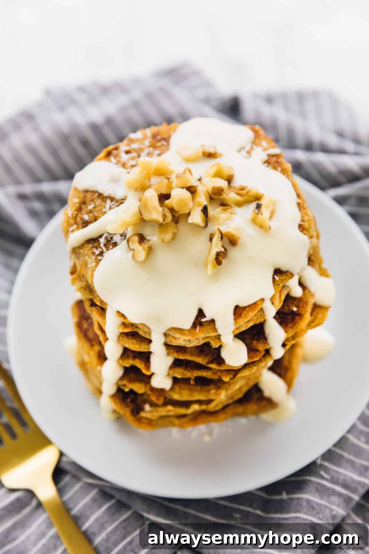 Vegan Carrot Cake Pancakes with Maple Cream Cheese 4 Top-down view of a stack of vegan carrot cake pancakes generously covered in a creamy maple cream cheese drizzle.