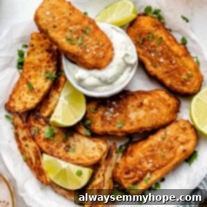 Overhead view of vegan fish sticks on parchment lined plate with one stick being dipped in sauce