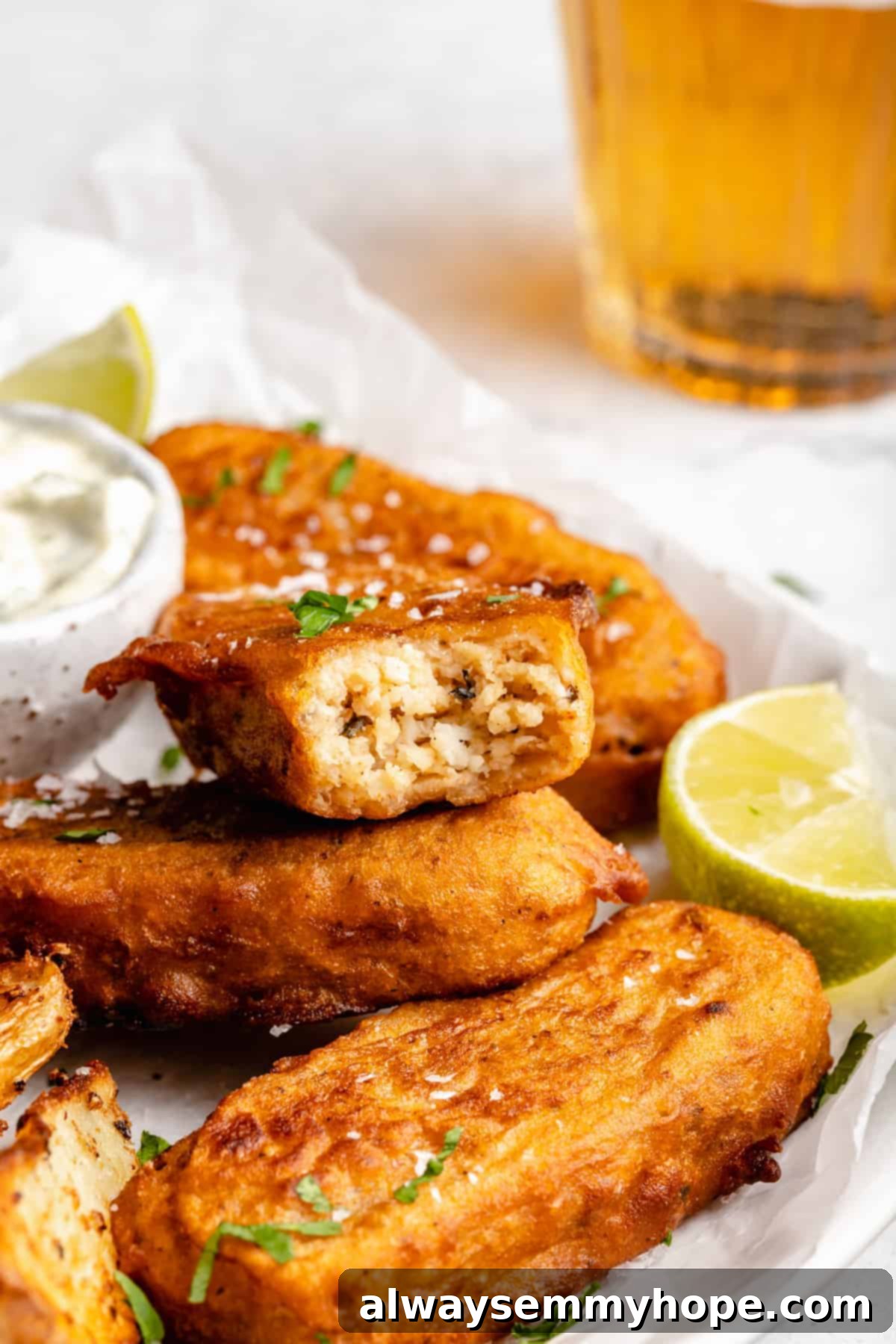 Closeup of a vegan fish stick with a bite taken out, revealing its flaky interior texture.