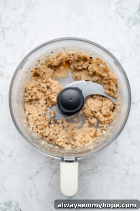Overhead view of the processed vegan fish stick mixture in a food processor, showing a flaky but cohesive texture.