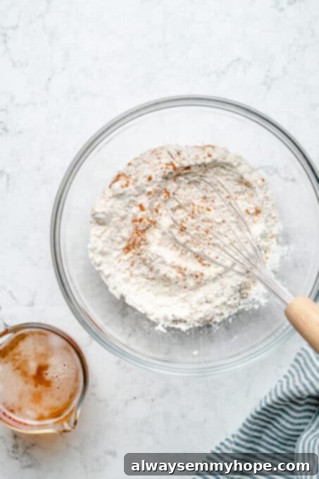 Overhead view of dry beer batter ingredients being whisked together in a glass bowl.