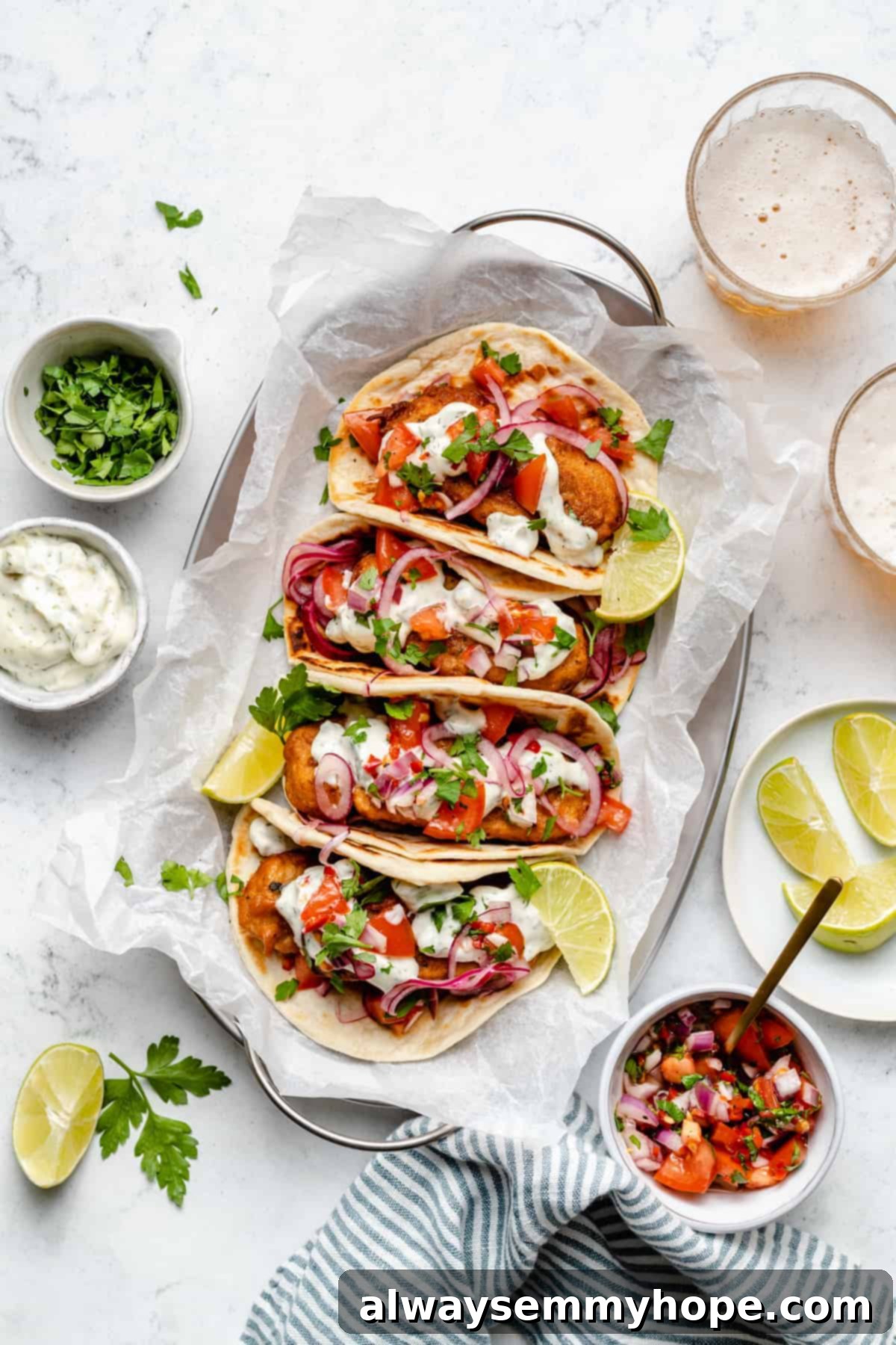 Golden Beer Battered Vegan Fish Tacos 5 Overhead view of fully assembled vegan fish tacos on a platter, surrounded by small bowls of garnishes like pico de gallo and tartar sauce.