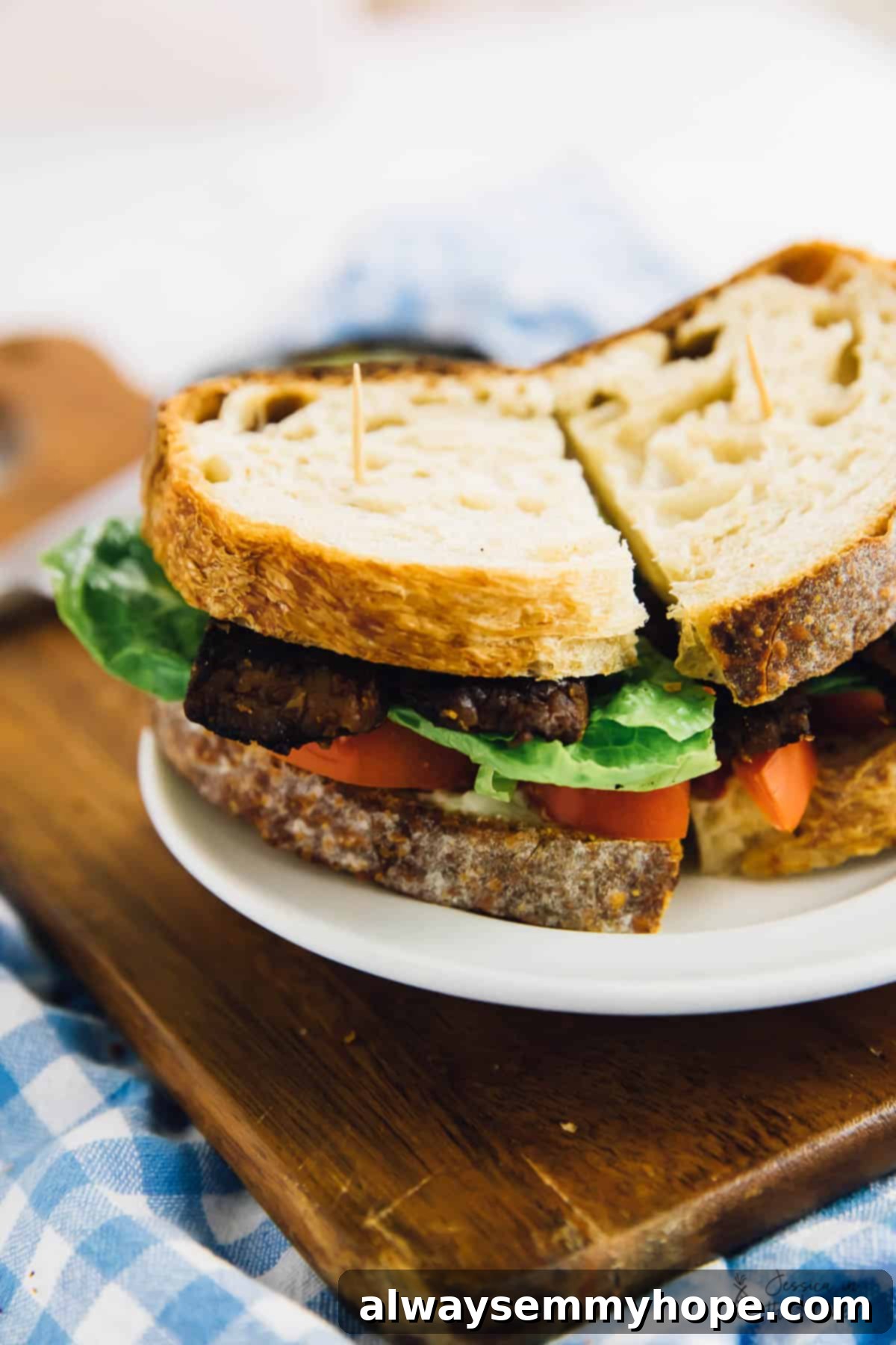 A perfectly assembled vegan BLT sandwich on a wooden cutting board, with vibrant colors of lettuce, tomato, and tempeh bacon, ready to be enjoyed.