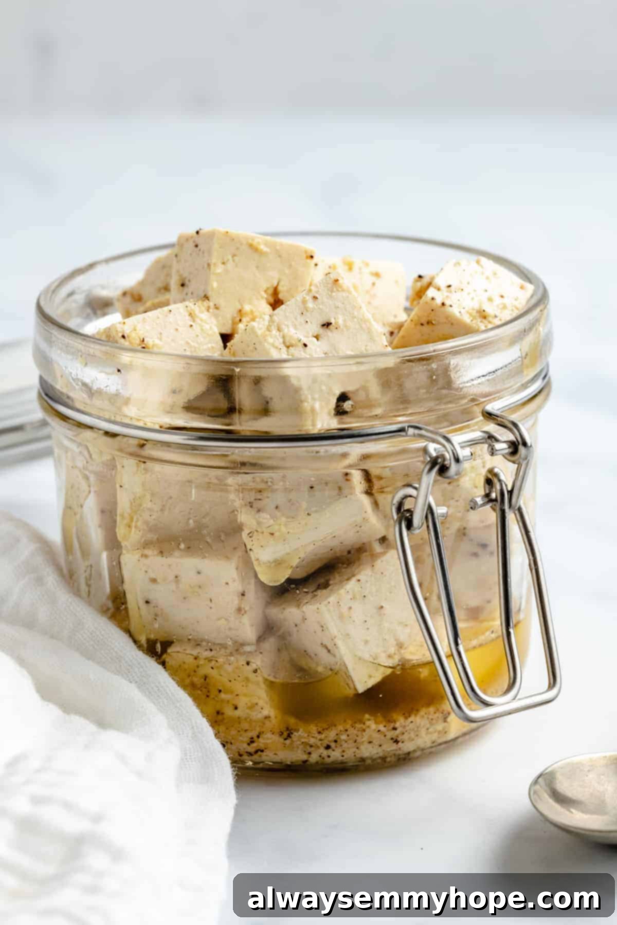 Vegan tofu feta cheese is a quick and easy plant-based substitute that needs only 6 ingredients. Enjoy it on salads, sandwiches, and more! tofu cheese in a clear jar